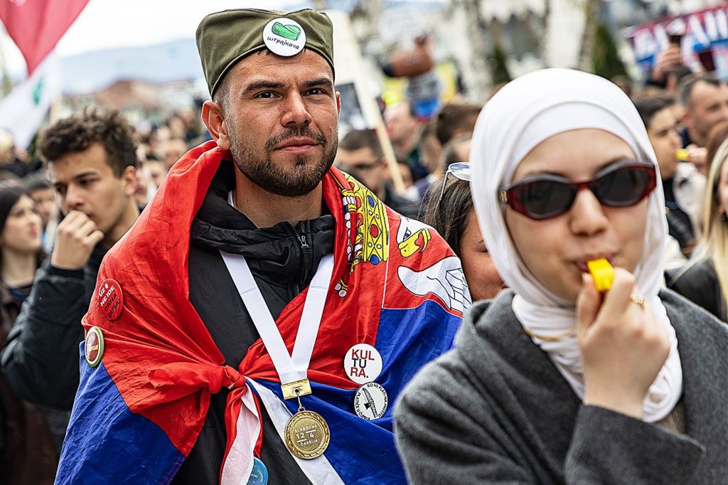 Serbian student protesters wearing Serbian and Bosniak Muslim traditional attires and a Serbian flag